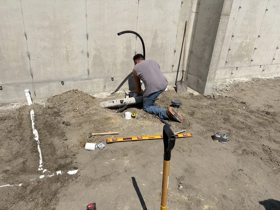 Plumbing crew working on drain pipes inside a new foundation