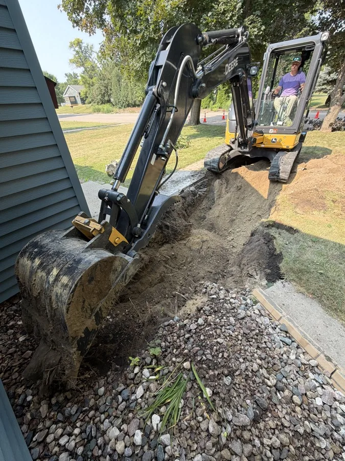 Excavated trench and equipment beside a home during sewer line work