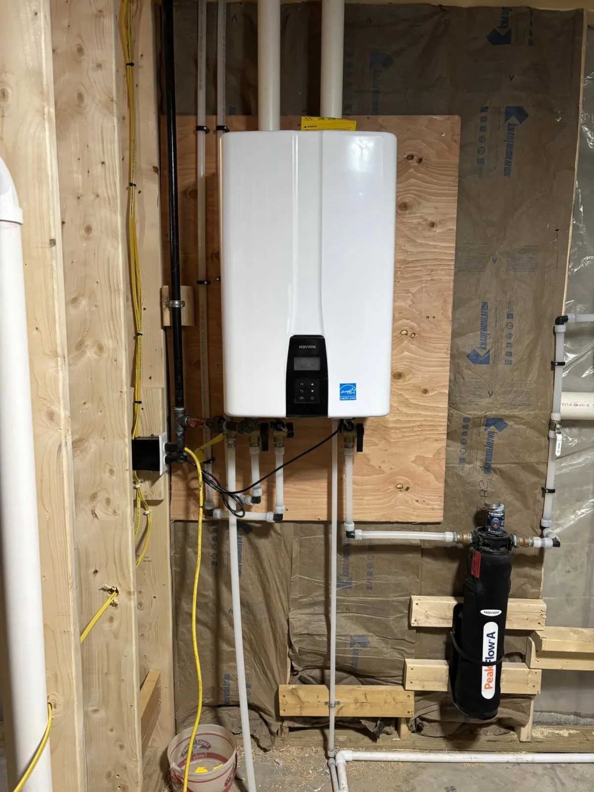 Wall-mounted tankless water heater with connected water piping and venting